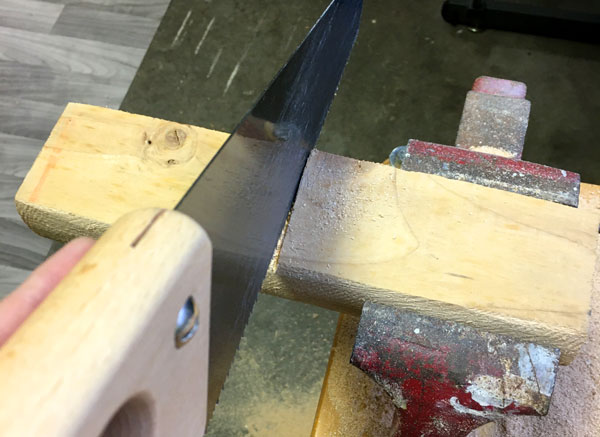 Cutting a piece of wood in half with a bench vice
